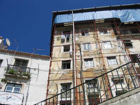 Dilapidated facade with red scaffolding and blue tarps, Alfama district, Lisbon
