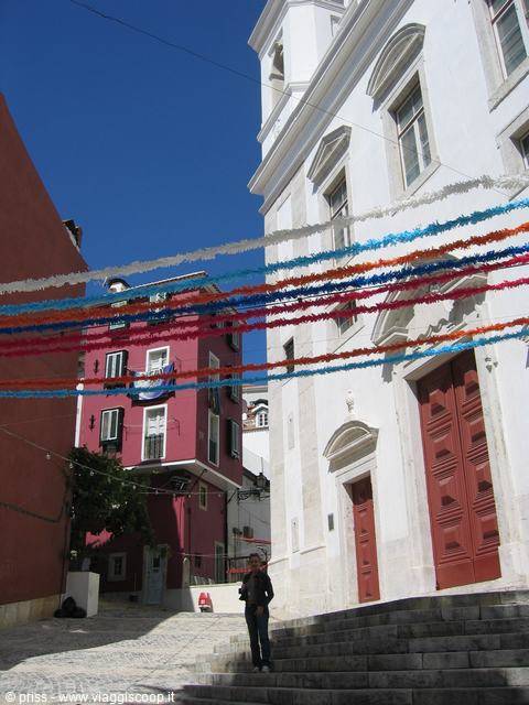 White church with red door in Lisbon, decorated with colorful paper garlands