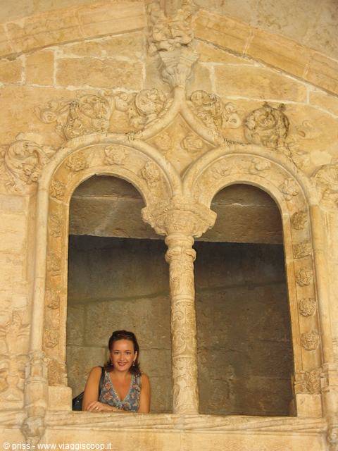 Smiling woman leaning out of ornate carved stone window, Jerónimos Monastery, Lisbon