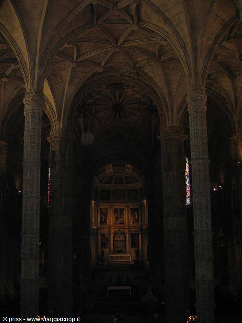 Inside the Jerónimos Monastery church, stone vaults and lit altar