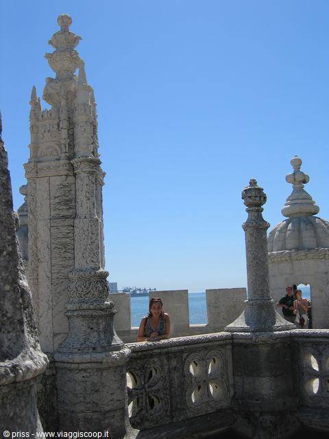 Tourist among the stone spires of Belém Tower, sea and ships behind