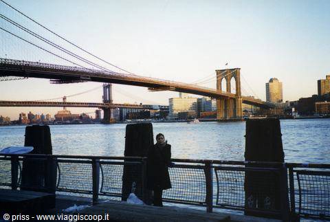 Woman by the railing in front of the Brooklyn Bridge over the East River