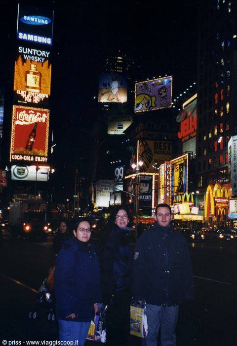 Friends in winter jackets among the glowing billboards of Times Square
