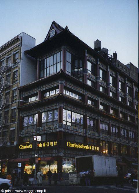 Chinese-style building in Chinatown, lit Charles Schwab signs at dusk