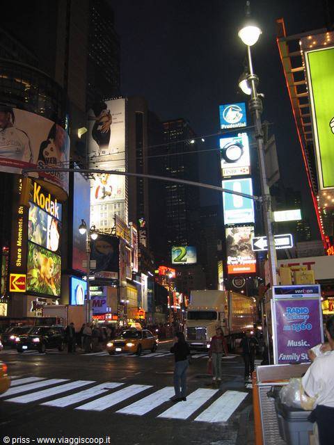 Times Square at night: glowing billboards, yellow taxis and pedestrians crossing