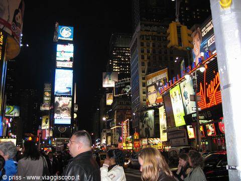 Crowd beneath the glowing billboards of Times Square at night, New York