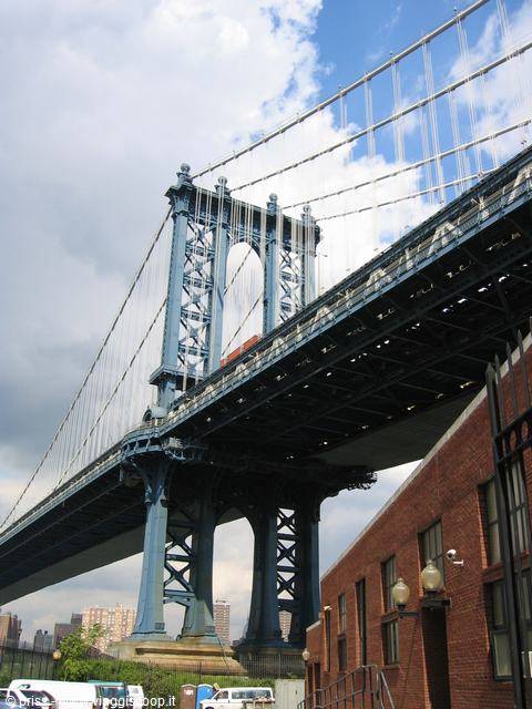 Steel tower of Manhattan Bridge rising over a red brick building