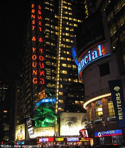 Times Square at night, glowing Ernst & Young, Chase and Reuters signs on skyscrapers