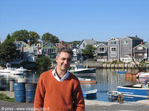 Man in orange sweater at Rockport harbor, wooden houses and fishing boats