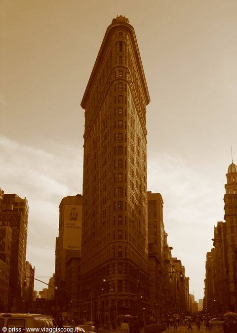 Flatiron Building in New York, brick facade, amber light, traffic below