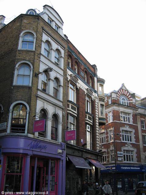 Purple shop signs and Victorian brick facades above pedestrians on the street