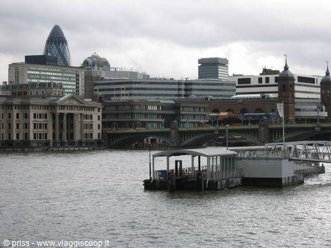 Covered pier on the Thames with the Gherkin skyscraper under a grey sky, London