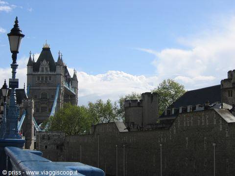 Stone Tower of London walls under white clouds, beside Tower Bridge