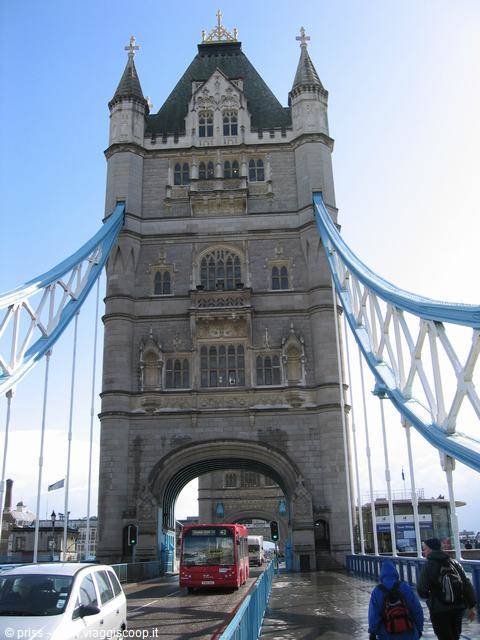Stone tower of London's Tower Bridge with red bus and pedestrians