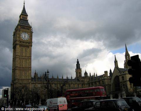 Big Ben and Parliament under dark clouds, red bus and taxis in London