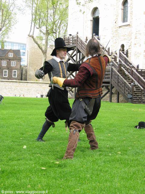 Two reenactors duel with swords on the grass at the Tower of London