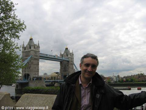 Smiling man in front of Tower Bridge in London under cloudy sky