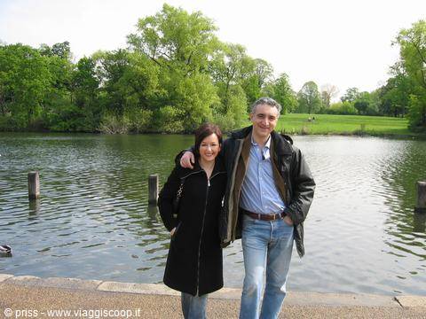 Couple in black jacket and jeans in front of a green park lake