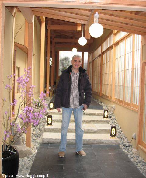 Turista in piedi su scalinata di legno tra lanterne e shoji di Miyajima