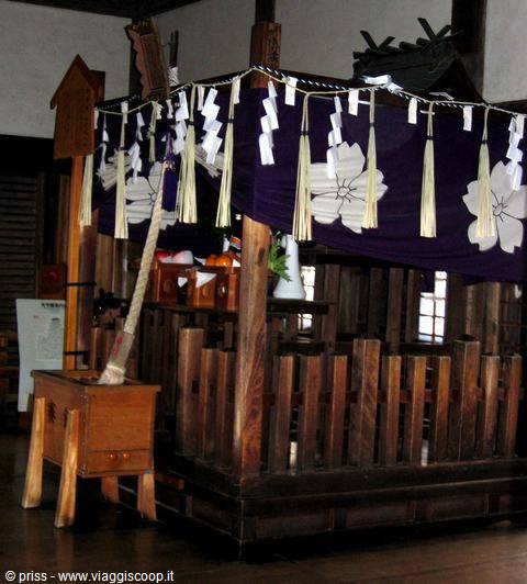 Altare in legno con corde shimenawa e bandiere viola, santuario interno