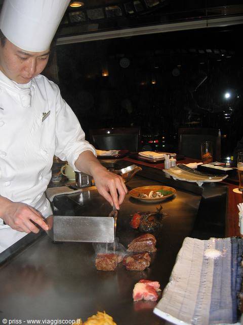 Cuoco teppanyaki affetta la carne sulla piastra d'acciaio, Kobe