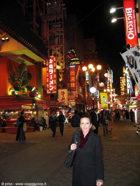 Smiling woman among neon signs and Big Echo billboard in Dotonbori, Osaka