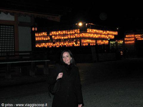 Una donna sorride sotto le lanterne accese del santuario Yasaka a Kyoto