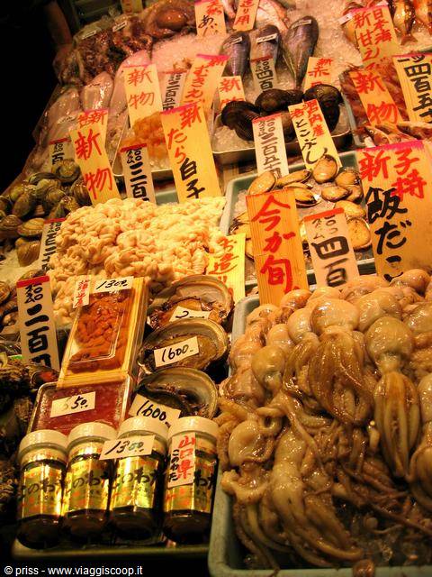 Banchi di pesce fresco e cartelli con prezzi al mercato di Tokyo