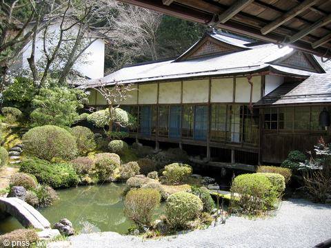 Wooden Japanese temple with tiled roof beside a pond garden