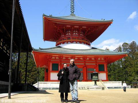 Sorrisi davanti alla grande pagoda vermiglia di Koyasan, cielo azzurro