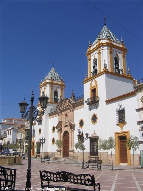 White church with green tiled towers, wrought iron benches under sunny blue sky