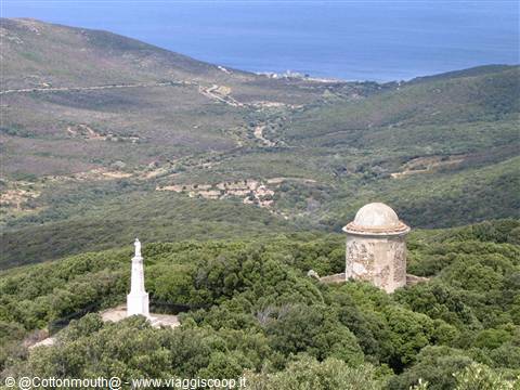 Old stone tower among Mediterranean scrub and white column facing the sea