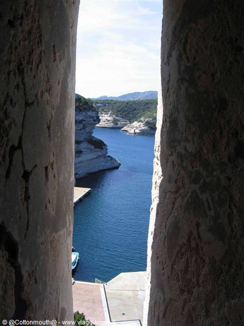 Bonifacio harbour seen through a narrow gap in old stone walls