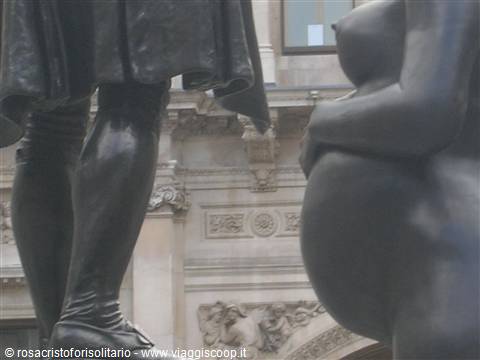 Bronze statue legs in front of a sculpted historic palace facade