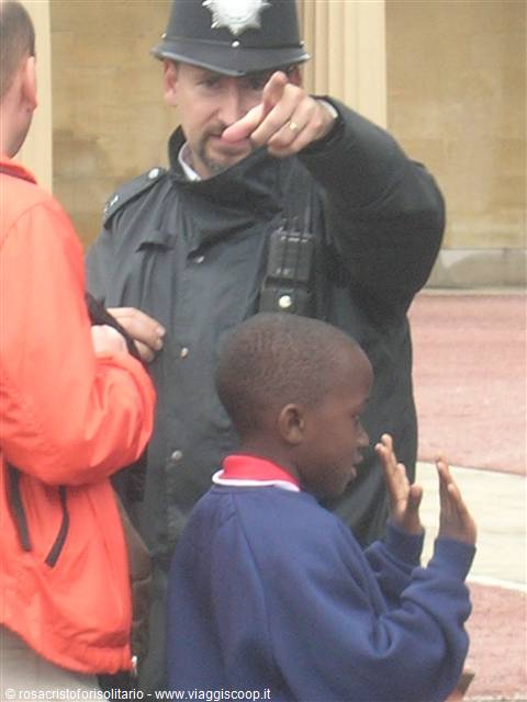Helmeted policeman points toward a clapping boy nearby