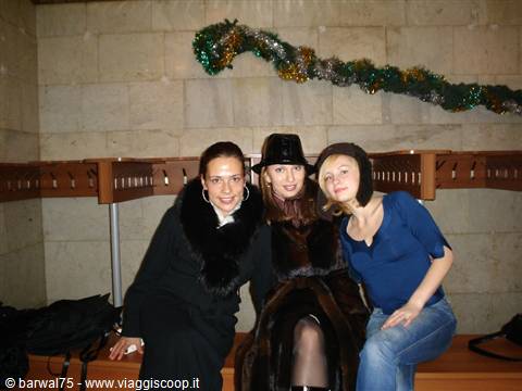 Three smiling girls in hats and fur coat at a theater cloakroom