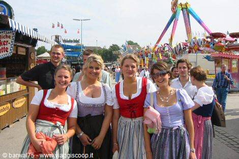 Girls in dirndl dresses at Munich Oktoberfest among stalls and colorful rides