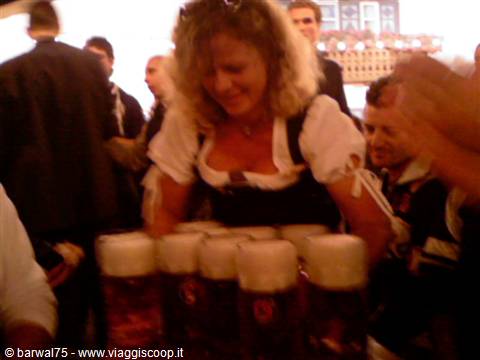 Waitress in dirndl serving frothy beers in a crowded hall