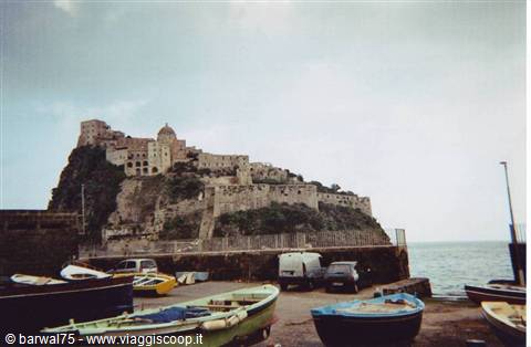 Colorful boats moored below the Aragonese Castle of Ischia among walls and sea