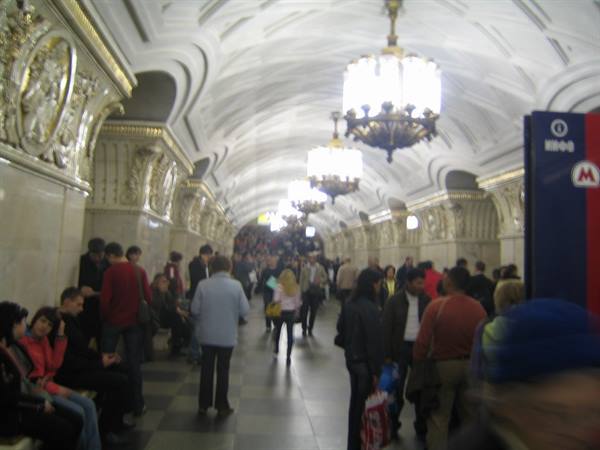 Commuters beneath chandeliers in the Moscow metro, white vaults and marble