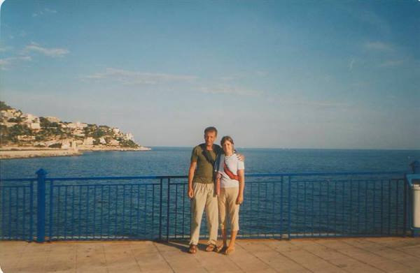 Couple standing on seaside promenade with blue railing by the sea