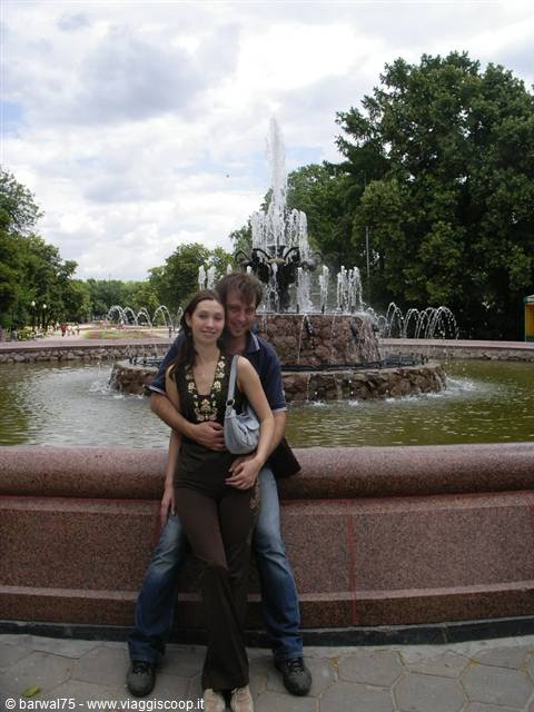 Couple hugging in front of the granite fountain in the city park