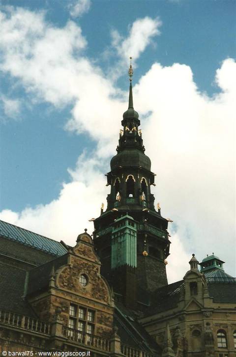 Baroque copper spire with golden details above brick façade, Copenhagen castle