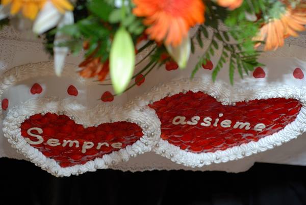 Wedding cake with two red strawberry hearts reading 'Sempre assieme', orange flowers above