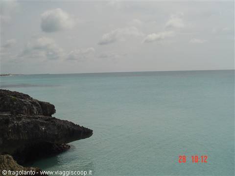 Dark rocks over turquoise sea under a cloudy sky