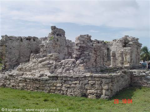Mayan stone ruins at Tulum, grassy walls under a cloudy sky