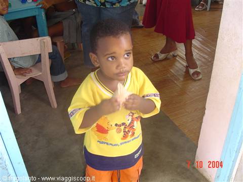 Toddler in yellow Winnie the Pooh shirt eats bread at nursery