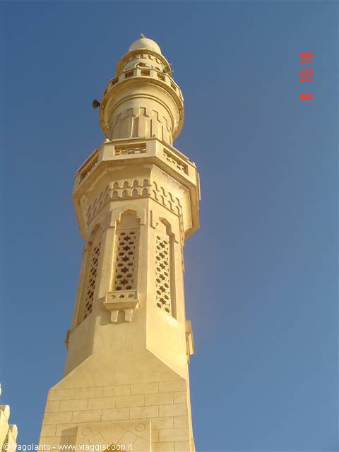 Light stone minaret with balconies and dome against blue sky