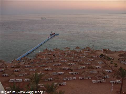 Floating jetty over the Red Sea, straw umbrellas on the beach at dawn