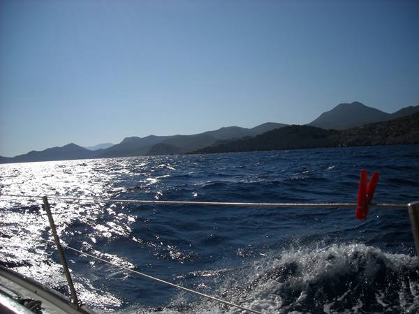 From a sailboat deck, choppy sea and mountainous coastline ahead